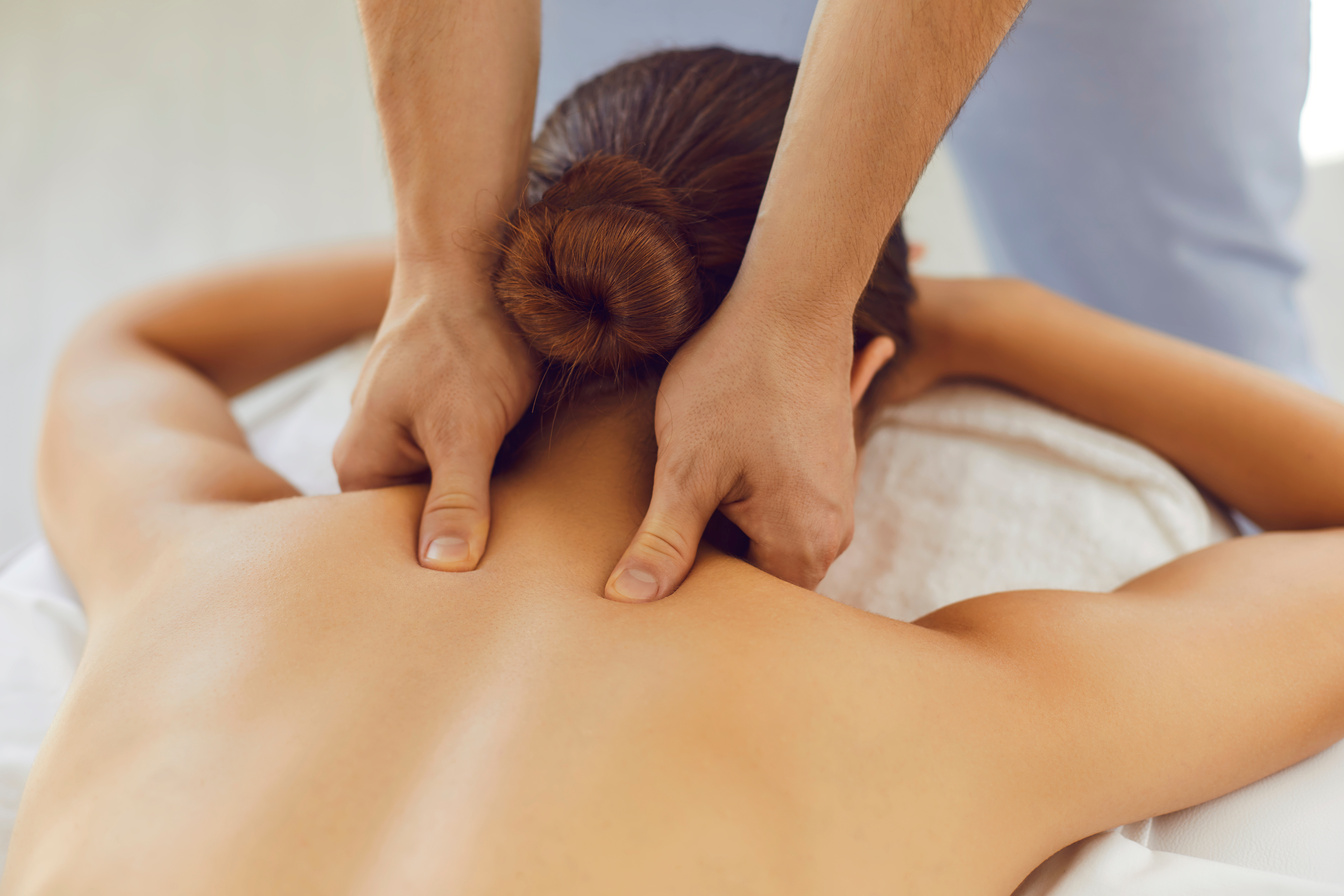 Men's Hands Do a Therapeutic Neck Massage for a Girl Lying on a Massage Couch in a Massage Spa.
